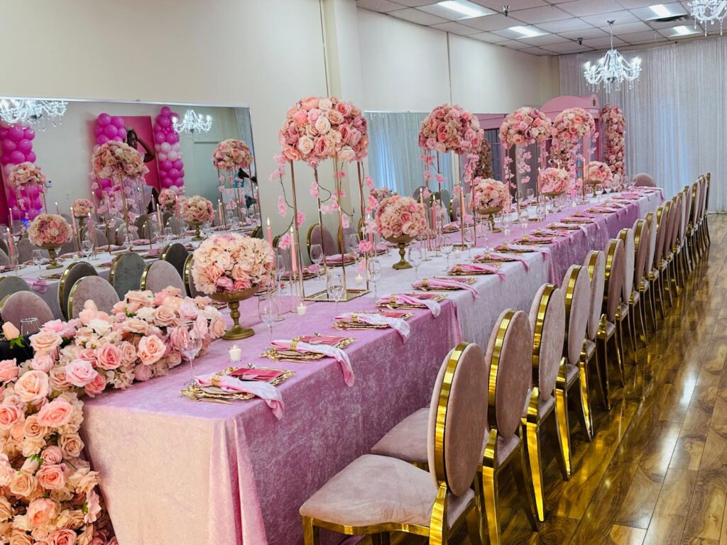 Rose centrepieces and gold-framed chairs along a dressed banquet table